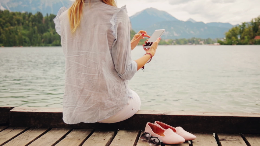 Girl on a wooden pier using smartphone.