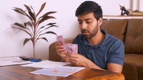 Worried Indian man counting money: Indian currency Rs 2000 notes - Making notes, calculating bills. HD stock video of a young man counting Indian currency/rupee notes and his expenses. Employee salary
