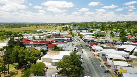 Aerial shot of the town of Beaudesert in the scenic rim region of Queensland Australia. Drone rises and orbits to reveal whole town centre during midday in Summer.