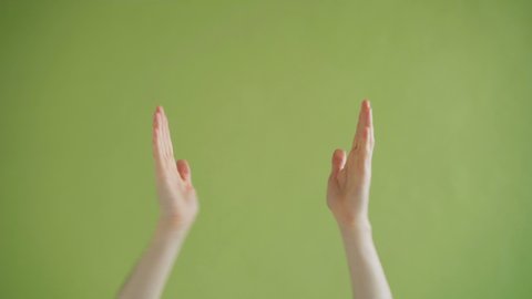 Close-up shot of human male hands clapping then showing thumbs-up gesture on green background. Applause, body language and high evaluation concept.