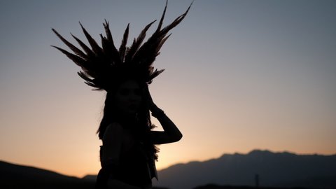 Native American girl in war bonnet  dark silhoulete on the sunse