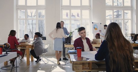 Camera slides left along trendy loft office, happy multiethnic business partners working at modern workplace atmosphere. – Video có sẵn