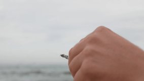 male hand with a cigarette close-up on the background of the sea. 4 k video