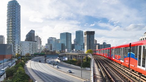 A London Docklands Light Railway trains arrive and leave East India station. Canary Wharf business district in the background.