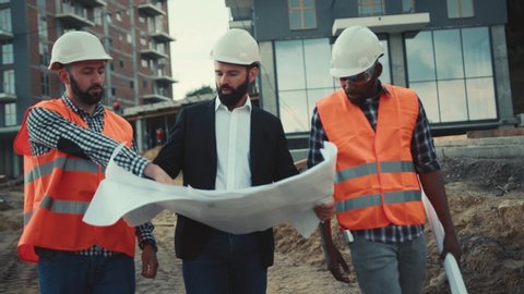 Handsome bearded architect and engineers inspect housing estate building to success construction plan before send quality housing to customers. Team work, agreement.