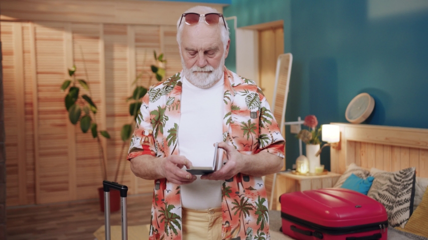 Portrait elderly tourist with sunglasses holding a travel voucher at home feel happy look at camera vacation travel senior old grandfather happy ensioner summer passport slow motion