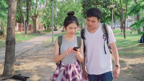 Slow motion - Traveler Asian couple direction on location map in Bangkok, Thailand, couple using mobile phone looking on map find landmark while spending holiday trip. Lifestyle couple travel concept.