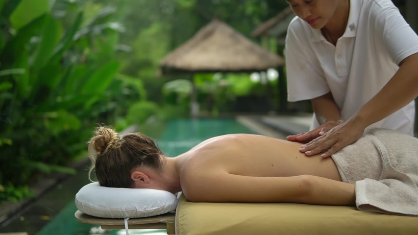 Girl client relaxing massage on special table beside the outdoor swimming pool | Shutterstock HD Video #1029694298