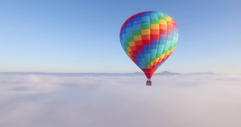 Colorful hot air balloon flying above high mountain over the fog at sunrise with beautiful sky background - Aerial drone view