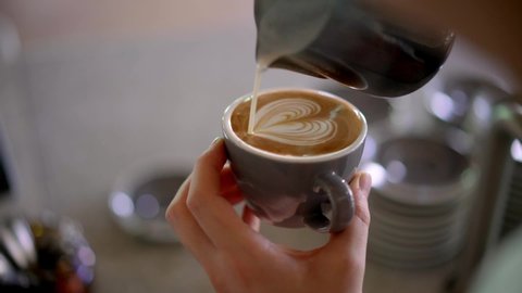Barista pouring milk in coffee doing latte art