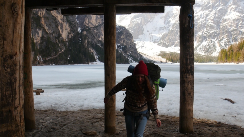 Young pretty woman walking on a lago di braies coast with a big backpack