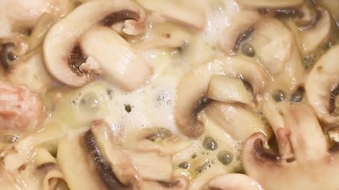 Mushrooms, fried in a pan in heated butter with onions and pepper. Mushrooms in the process of stewing and frying in a pan in butter
