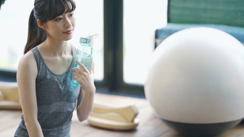 Young asian girl in fitness gym. Rehydration concept.