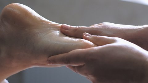 Professional massage therapist does a foot massage to a young woman.