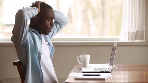 Frustrated upset black man using laptop reading bad news online, shocked depressed sad african american male user feeling despair looking at screen stressed about bankruptcy debt or computer problem