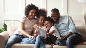 Cute little african children play online game using digital tablet having fun with parental control sit on sofa, happy black family laugh look at computer screen together enjoy do internet shopping - Powered by Shutterstock - Get 15% off with code: PIKWIZARD15