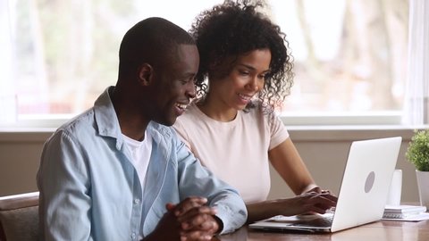 Euphoric happy overjoyed young african american family couple looking at laptop computer feel winners excited by online lottery bid win celebrate good internet news victory achieved new opportunity