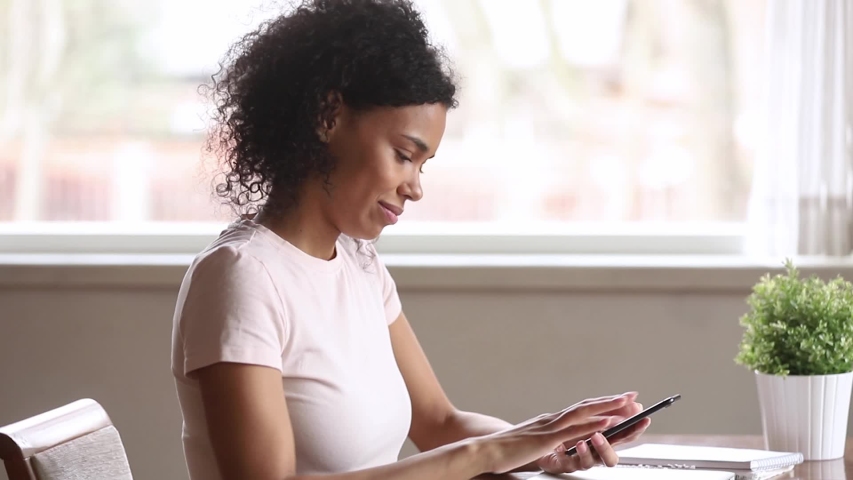 Smiling african american woman using smartphone dating app looking swiping on screen, happy mixed race young girl holding phone enjoy watching media in mobile online application on cellphone Royalty-Free Stock Footage #1029714110