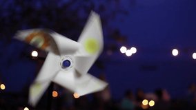 Spinning pinwheel or paper wind mill with blue sky and light bokeh background.Close up shot.Beach scenery at night.