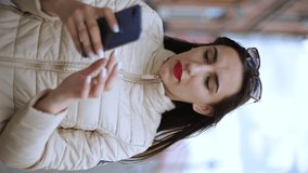 vertical video. Surprised young woman using smart phone outdoors