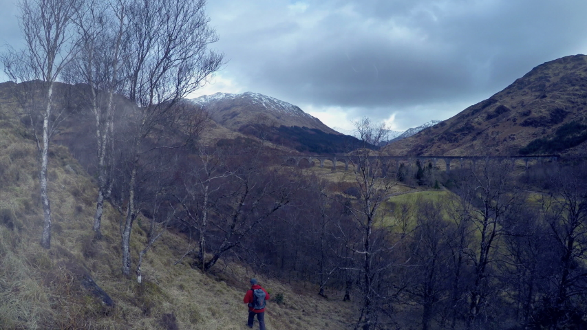 4K traveller backpacking near Glenfinnan viaduct in Scotland, United Kingdom. Famous movie location in Scottish Highlands.