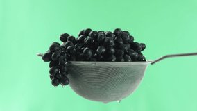 in the video we see grapes in a sieve, water start fall from the top then stop, green background