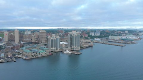 Cinematic drone / aerial footage rotating showing waterfront docks and buildings, the port and Angus L. Macdonald bridge in Halifax, Nova Scotia, Canada during summer season.