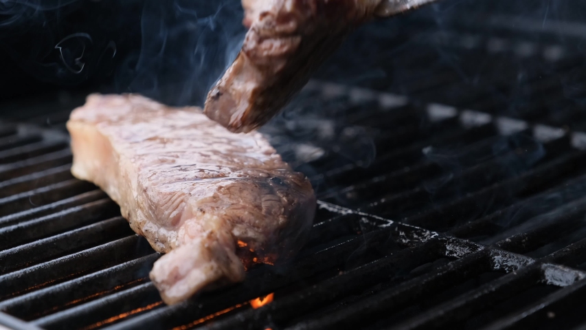 grilling steaks on flaming grill and shot with selective focus Royalty-Free Stock Footage #1029742538