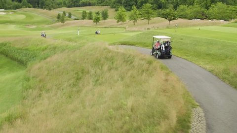 Street level view of golfers and caddies on golf carts
