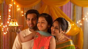 Nuclear Indian family portrait : Little daughter lighting diyas. Complete Family in India. Indian stock video of a happy nuclear family celebrating Diwali together by lighting their house with diya - Powered by Shutterstock - Get 15% off with code: PIKWIZARD15
