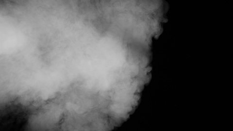 White Smoke Pours Over Black Background. A cloud of white smoke slides over the black screen and gradually covers it