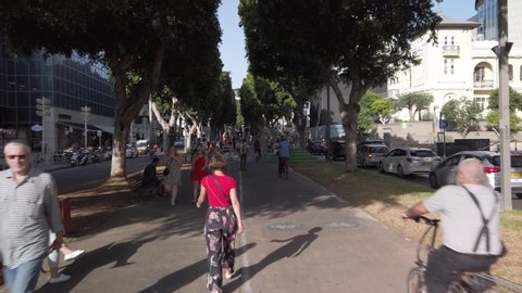 Tel Aviv - May 15th 2019: HyperLapse moving up Rothschild Boulevard, in the shade of the Avenue trees, between pedestrians, bicycles and scooters.
