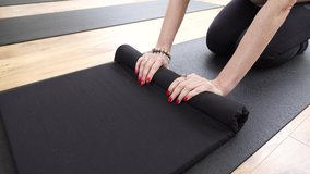 
4K video. Yoga studio, girls warm up in the yoga room, warm up their arms and legs, on a black sports mat, in sporting leggings and top. 4K UHD 25p ProRes HQ 422