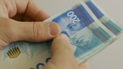 Counting 200 Israeli shekel bills - close up on large amount of money
