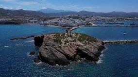 Aerial drone panoramic view video of iconic and unique Temple of Apollon or Portara (Gate) with breathtaking views to port - town and castle of Naxos island and the Aegean blue sea, Cyclades, Greece
