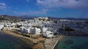 Aerial drone video of iconic chora, main town of Naxos island featuring beautiful uphill castle views to the Aegean deep blue sea and Temple of Apollon at the background, Cyclades, Greece