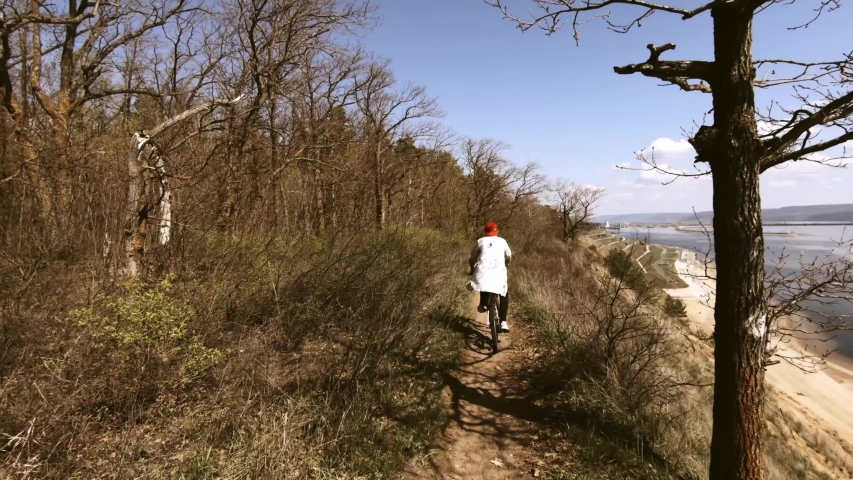 Cycling through the forest and the park. First person shooting. Travel along the path on the edge of a cliff above the river. POV