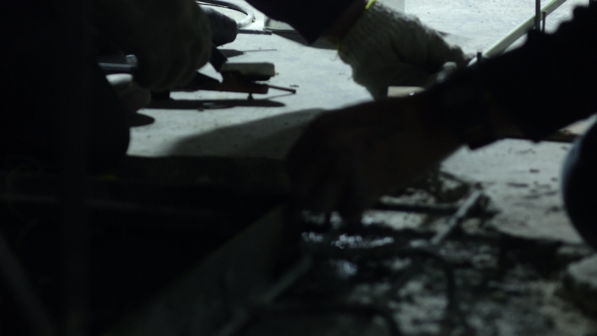 4K UHD footage of a skilled steel welder working on metal construction structure in a factory setting with bright sparks and focused movement.