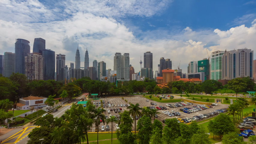 Time lapse of high angle view near Kuala Lumpur city skyline from afar during blue sky morning in Malaysia.