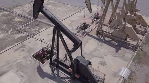 Drone Flight Past Working Pumpjack ndustrial oil pump jack working and pumping crude oil for fossil fuel energy with drilling rig in oil field