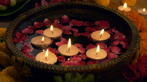 Diwali decoration - woman keeping floating candles in a bowl / urli - Diwali Celebration.