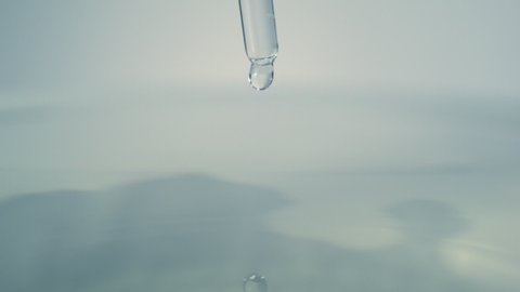 Water dropper in slow motion. Drop falling from pipet in water and making ripples filmed with high speed camera
