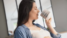 Pregnant woman drinking tea in front of laptop