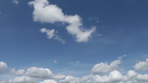 White cumulus clouds float across the blue sky. Timelapse sky clouds.