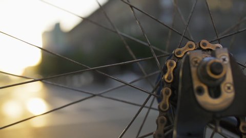Rotating bicycle wheel closeup at city sunset. Ecological urban transport. Bike detail macro shot. Defocused city street life on background