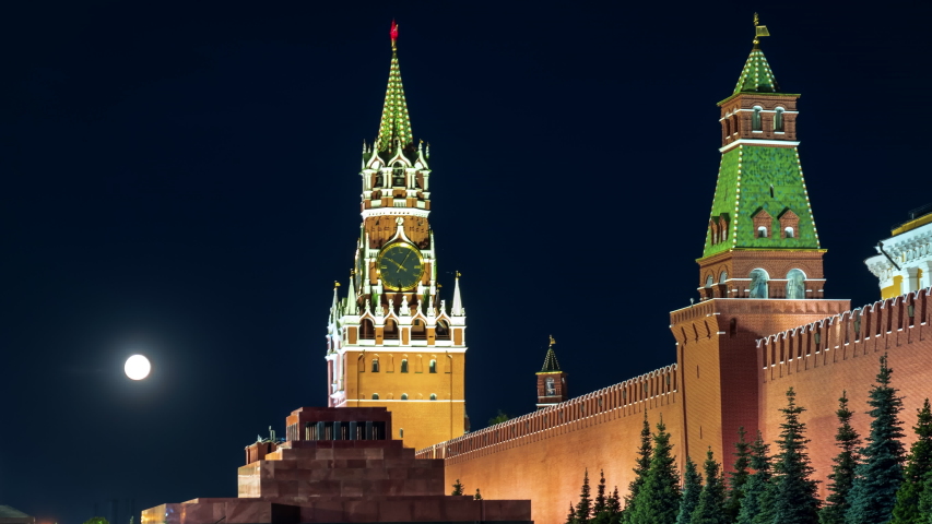 Full moon floating in the night sky over the Moscow Kremlin. Time lapse of the Kremlin wall, the Spasskaya tower and Lenin