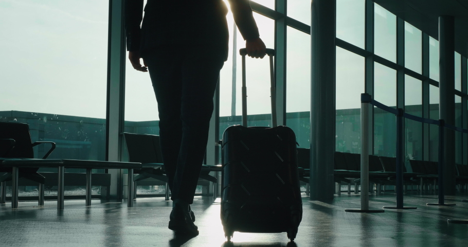 Slow motion of an young elegant businessman in a suit is walking with a suitcase in the international airport with a sunshine from the window. Royalty-Free Stock Footage #1029851108