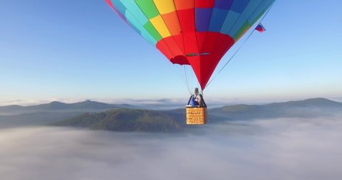 Стоковое видео: Colorful hot air balloon flying above high mountain over the fog at sunrise with beautiful sky background - Aerial drone view