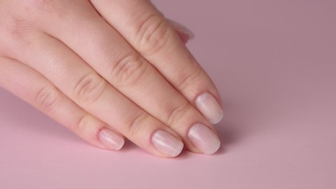 closeup woman hand on pink and other hand tpuches another.Ideal natural manicure