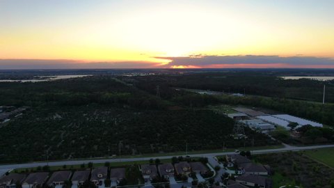 Flying over lakeside neighborhood and orange tree farm during a beautiful Florida sunset